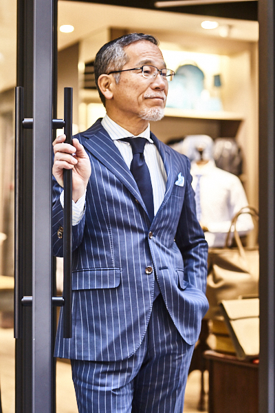クラシックなストライプスーツをモダンに着こなす好例。適度にゆったり感のあるサイジングと襟型がポイントです。 – Azabu Tailor Style